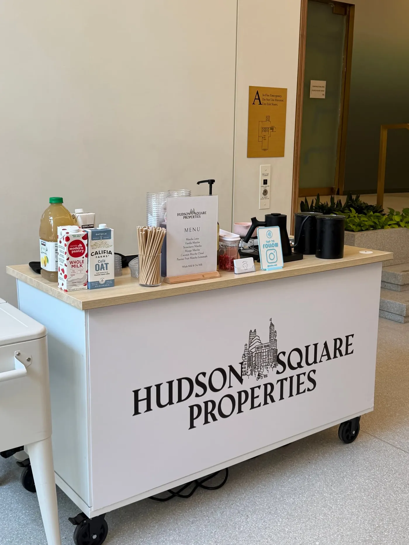 White coffee cart wrapped with the Hudson Square Properties logo in an office lobby