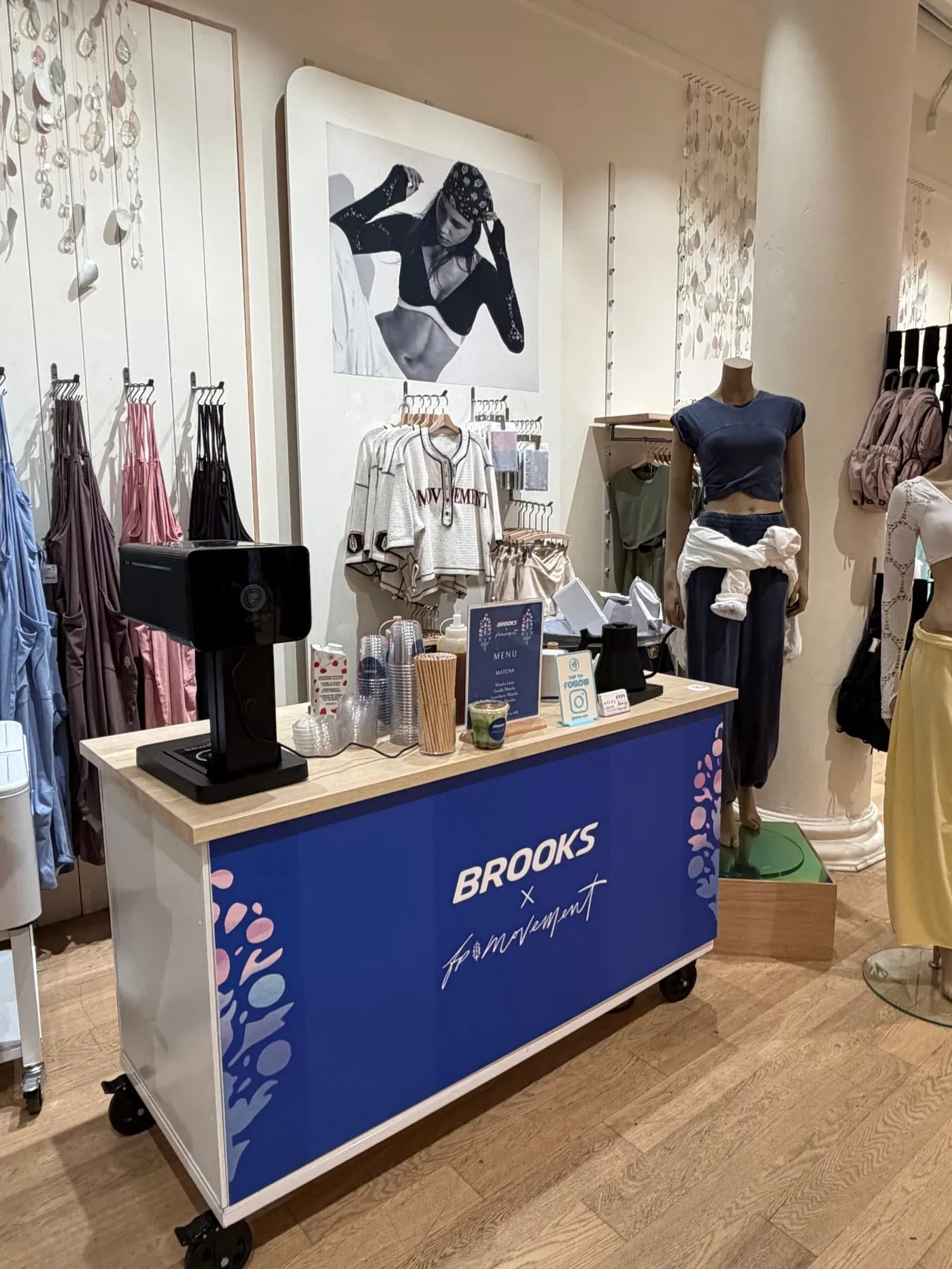 Blue coffee cart wrapped with Brooks x FP Movement branding inside a retail store