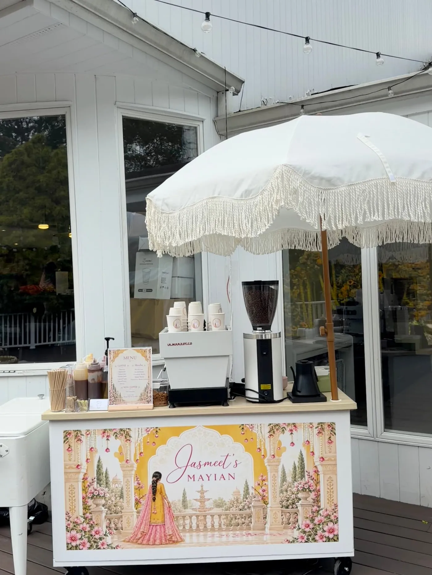White coffee cart with a fringed parasol and an illustrated wrap for a wedding Mayian celebration