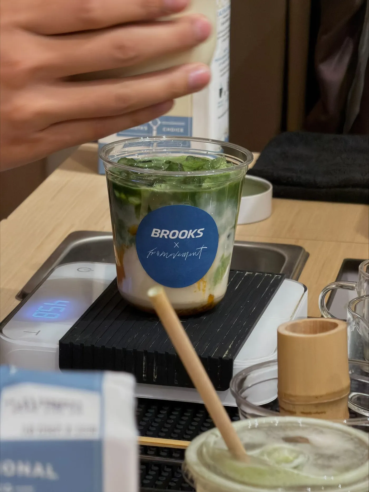 Iced matcha latte in a cup with a Brooks x FP Movement sticker